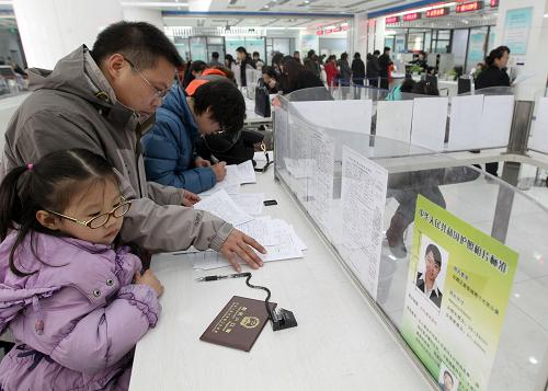12月19日,一位父親帶著女兒在北京東城區(qū)行政服務(wù)中心二層的出入境接待大廳填表辦理證件。新華社記者 張宇 攝