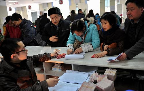 12月23日,在湖北宣恩縣勞動社會保障大廳,工作人員為新參保的國有、集體企業(yè)職工發(fā)放退休證。新華社發(fā)(宋文 攝)