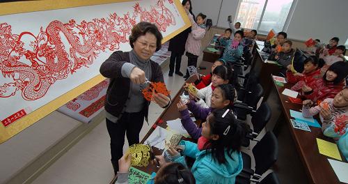 12月26日,遼寧省錦州市太和小學(xué)美術(shù)老師在指導(dǎo)學(xué)生創(chuàng)作有關(guān)龍的剪紙。新華社發(fā)(李鐵成 攝)