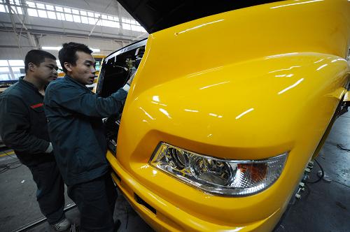 12月26日,恒通客車總裝車間的工人在為校車安裝發(fā)動(dòng)機(jī)。新華社記者 李健 攝