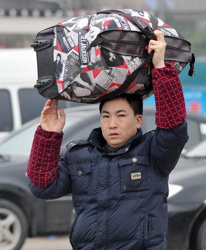 1月19日,旅客頭頂行李趕往長(zhǎng)沙火車(chē)站。新華社記者 龍弘濤 攝