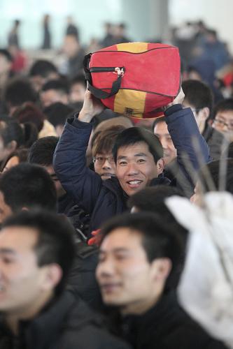 1月19日,在煙臺火車站西候車室,旅客頭頂行李排隊檢票。當(dāng)日,2012年全國鐵路運輸進入春節(jié)前客流高峰。山東煙臺火車站預(yù)計運送旅客1.6萬余人,比春運第一天增加4000余人。 新華社發(fā)(申吉忠 攝)