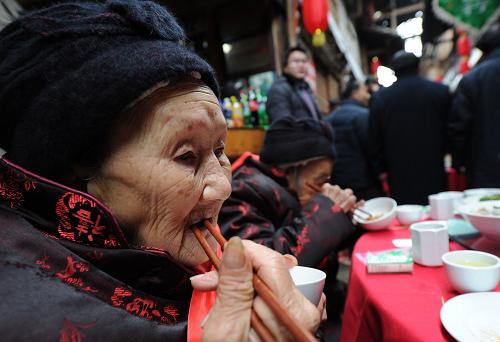 1月21日,86歲的徐朝清老人在“千米長宴”上品嘗美食。新華社記者 李健 攝
