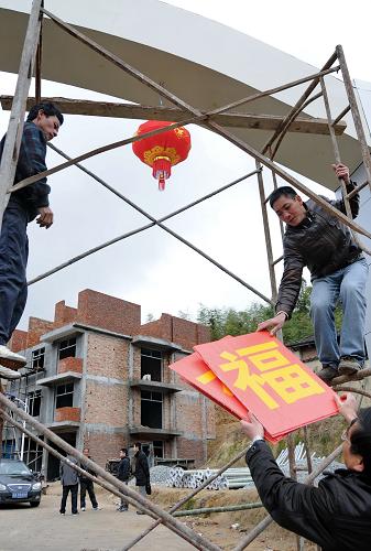 1月31日,東姚村村民在安置房小區(qū)入口拱門上張貼“東姚造福工程”字樣。新華社記者 林善傳 攝