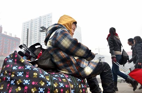 2月6日,在鄭州火車站廣場(chǎng),一位男童坐在行李上等候進(jìn)站。新華社記者 王頌 攝