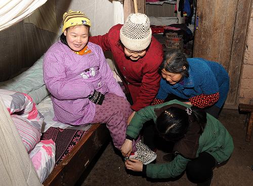 2月11日,重慶市云陽縣黃石鎮(zhèn)中灣村“貼心嫂子”互助組組員彭志竹(前右)等為該村患有腦癱的困難婦女張萬英(左一)穿鞋,準備帶她外出散心。自2011年以來,重慶市云陽縣婦聯(lián)通過基層婦女干部或婦女能人帶動,成立“貼心嫂子”互助組,提高本縣留守婦女抵御困難及風(fēng)險的能力。目前,全縣已組建各類農(nóng)村留守婦女“貼心嫂子”互助組4610個,吸納留守婦女36800余人,基本實現(xiàn)了互助小組村村覆蓋。新華社記者 何俊昌 攝
