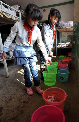 2月21日,云南省陸良縣小百戶鎮(zhèn)羅貢村小學(xué)的兩名女學(xué)生將取來的水放在宿舍里。新華社記者 藺以光 攝