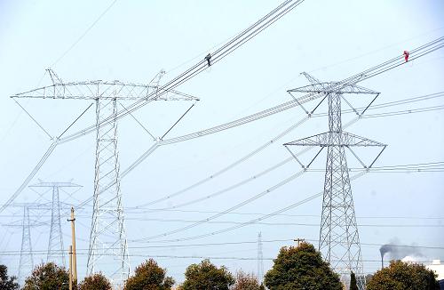 3月13日,浙江省湖州電力局工作人員在高空檢查±800千伏錦蘇特高壓直流輸電工程浙江湖州段電纜導(dǎo)線情況。新華社記者 徐昱 攝