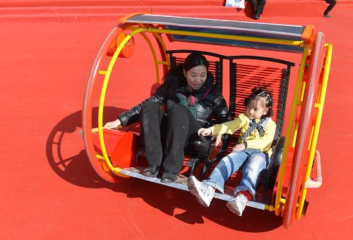 3月14日,一名小朋友在家長的帶領(lǐng)下在博覽會上體驗“逍遙車”。新華社記者李俊東攝