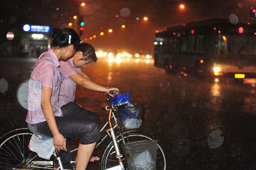 7月27日晚,在北京市宣武門地鐵站附近,兩名女子在大雨中騎行。新華社發(fā)(劉長(zhǎng)龍 攝)