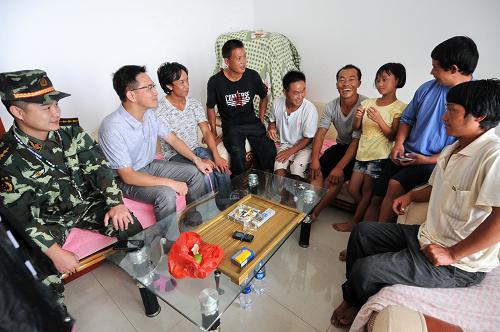 8月3日,為了不讓漁民臺風(fēng)剛過馬上擅自出海,羅源邊防武警戰(zhàn)士許小華(左一)和駐村紀(jì)檢工作人員廖應(yīng)鏗(左二)到回港避風(fēng)的漁民家里作動員工作。新華社記者 林善傳 攝