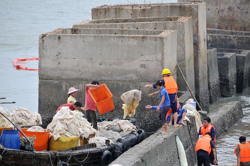 工作人員用小船清理油氈(8月18日攝)。新華社記者閆祥嶺攝