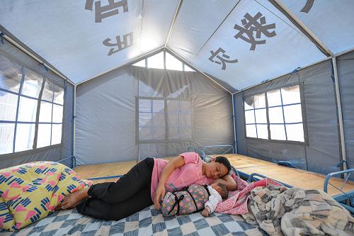 9月14日,產(chǎn)下男嬰剛兩天的馮明英在彝良縣婦聯(lián)設(shè)立的“產(chǎn)婦帳篷”內(nèi)哄嬰兒入睡。新華社記者 李鑫 攝