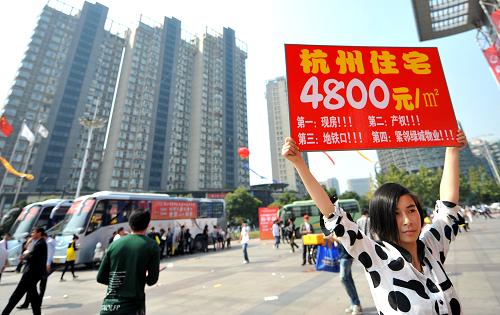 10月20日,一名房產(chǎn)推銷人員正在浙江省房博會會場外推銷一處杭州遠郊低價樓盤。新華社記者 王定昶 攝