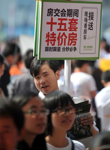 10月20日,一名房產(chǎn)推銷人員正在浙江省房博會會場外推銷一處杭州遠郊低價樓盤。新華社記者 王定昶 攝