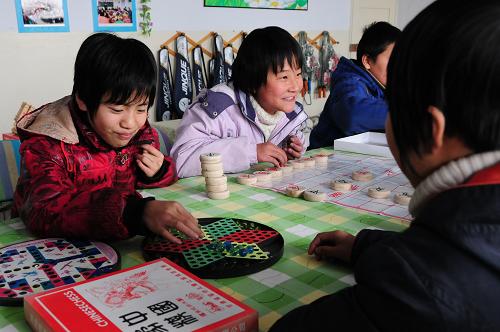 12月6日,在張掖市甘州區(qū)黨寨鎮(zhèn)中心學(xué)校的留守兒童之家,留守兒童郭靜(左一)和好朋友一起下跳棋。新華社記者 范培珅 攝