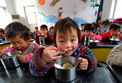 12月19日,青龍滿族自治縣七道河鄉(xiāng)后水河小學的王月(右)和同學一起享用免費午餐。近日,由中國社會福利教育基金會發(fā)起的“貧困山區(qū)小學生免費午餐行動”讓河北省青龍滿族自治縣七道河鄉(xiāng)后水河小學的80個孩子吃上了免費午餐,成為河北省首個實施免費午餐項目的學校。據(jù)介紹,這所學校80個孩子都是山區(qū)貧困農(nóng)村的孩子,他們當中很多孩子上學要走近10公里的山路,中午只能是由家中帶兩個饅頭幾根咸菜,有的就到學校附近的小商店內(nèi)買包方便面干吃。2012年9月,中國社會福利教育基金會的工作人員到學??疾旌?,決定從12月1日開始,每天為每個孩子捐贈3元錢的午餐費,學校也請來了專職人員,每天中午為孩子們做午餐。新華社記者 楊世堯 攝