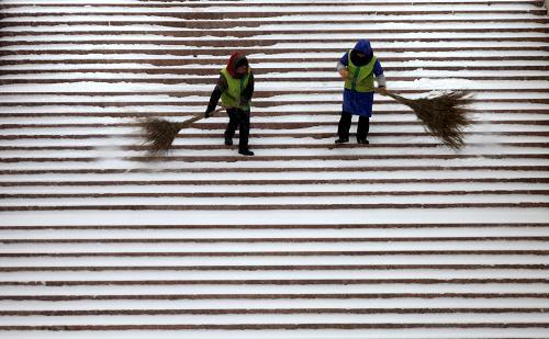 12月23日,園林工人冒雪在威海市幸福公園的臺階上清理積雪。受冷空氣影響,山東省威海市12月22日夜間開始降雪,氣溫明顯下降。新華社發(fā)(于啟波 攝)