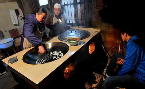 1月21日,在湖北省恩施土家族苗族自治州宣恩縣,湖塘社區(qū)的居民在家中烙“豆皮”。新華社發(fā)(宋文 攝)