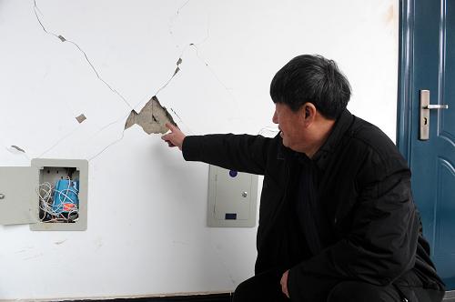 1月23日,遼寧省遼陽市燈塔市柳條寨鎮(zhèn)政府工作人員向記者介紹被地震震裂的政府房屋墻壁。