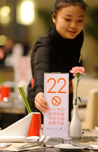 1月24日,青島海景花園大酒店,一名員工在更換印有“厲行節(jié)約、文明用餐”提示的桌號牌。新華社記者 李紫恒 攝