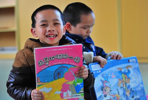 1月24日,已經(jīng)7歲的被拐兒童江懷仁(左)拿著愛心慰問禮物和學(xué)習(xí)用品。新華社記者 魏培全 攝