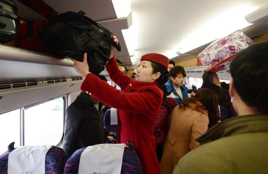 1月26日,在南昌火車站,一名乘務(wù)人員在幫助旅客擺放行李。新華社記者 周科 攝