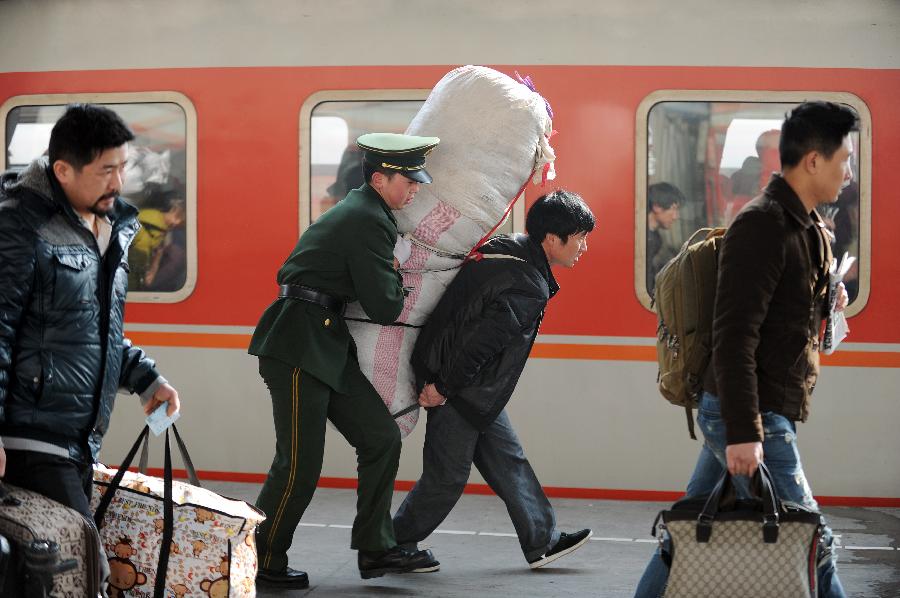 1月26日,一位在杭州火車站執(zhí)勤的武警戰(zhàn)士在幫助一位返回云南昭通的旅客托行李背包。新華社記者鞠煥宗攝