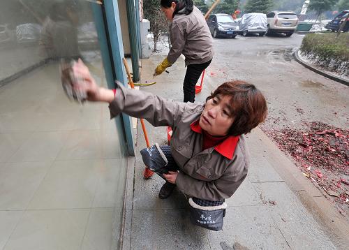 2月10日,在江西省南昌市濱江豪園小區(qū),清潔工人在擦洗一處單元樓玻璃。昨夜,因居民在附近燃放煙花爆竹導致玻璃被熏黑。新華社記者 彭昭之 攝
