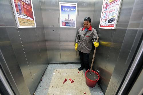 2月10日,在江西省南昌市濱江豪園小區(qū)一棟單元樓的電梯內(nèi),清潔工在清掃擦洗樓道內(nèi)燃放爆竹后留下的殘渣。新華社記者 彭昭之 攝