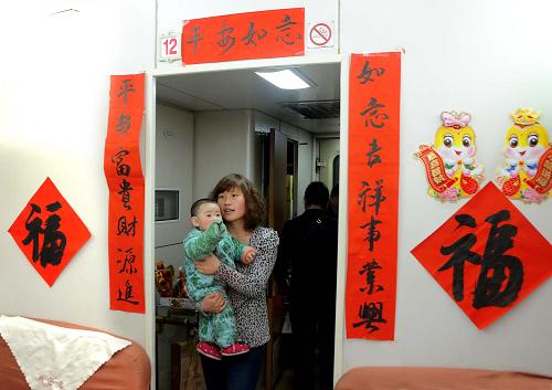 2月11日,一名乘客抱著孩子走進(jìn)裝扮得十分喜慶的餐車。新華社記者王頌攝