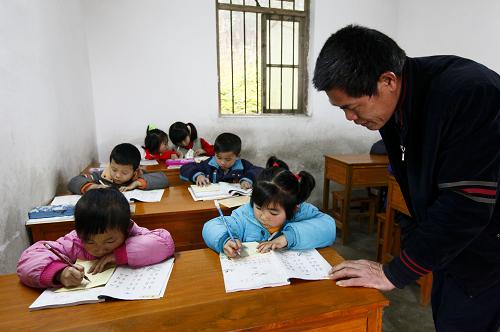 2月25日,在廣西柳城縣古砦仫佬族鄉(xiāng)大巖垌教學(xué)點(diǎn),潘善吉老師在指導(dǎo)學(xué)生寫生字。新華社發(fā)(鄧克軼 攝)