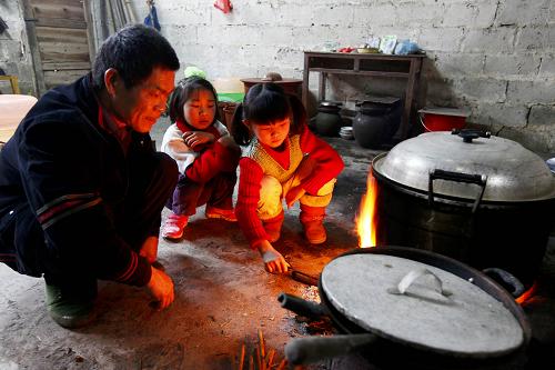 2月25日,在廣西柳城縣古砦仫佬族鄉(xiāng)大巖垌教學(xué)點(diǎn),潘善吉老師和學(xué)生們一起燒火煮飯。新華社發(fā)(鄧克軼 攝)