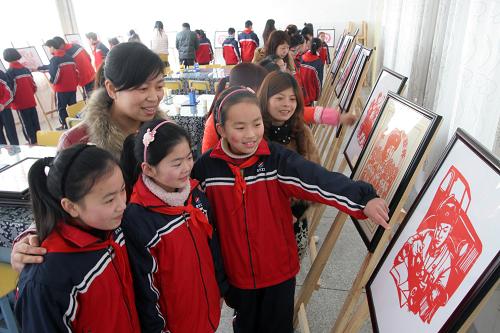 3月3日,在浙江省湖州市德清縣乾元鎮(zhèn)中心小學(xué)剪紙室,莫依晨(前左四)向大家介紹她創(chuàng)作的《雷鋒義務(wù)修車》剪紙作品。新華社發(fā)(倪立芳 攝)