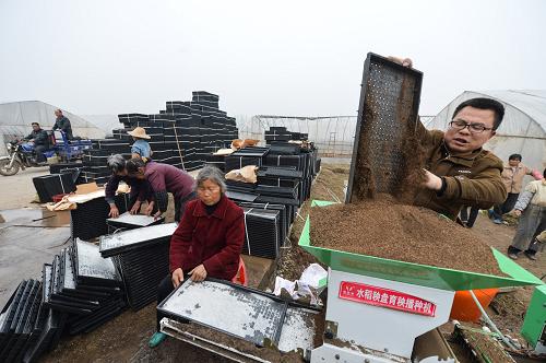 3月14日,一名村民在向生產(chǎn)線內(nèi)填裝育秧土。新華社記者 白禹 攝