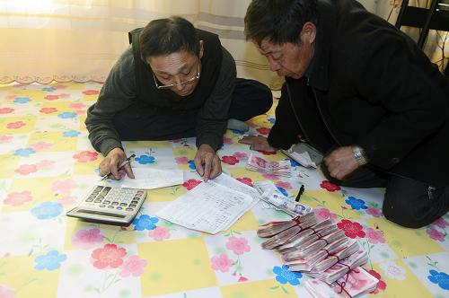 3月16日,李虎春(右)與合作社會(huì)計(jì)吳德全在為今年備種蘋果做預(yù)算。新華社記者 林宏 攝