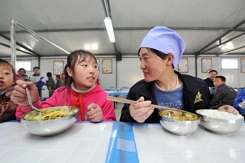 3月20日,在寧夏回族自治區(qū)西吉縣吉強(qiáng)鎮(zhèn)夏寨小學(xué),學(xué)生家長(zhǎng)和孩子們一起品嘗免費(fèi)午餐。新華社記者 彭昭之 攝