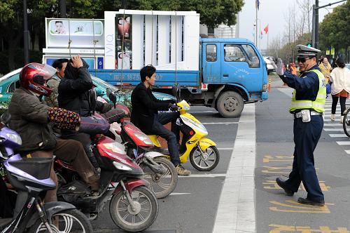3月21日,杭州市公安局交通警察局一名協(xié)勤(右)在指揮電動(dòng)車駕駛員按照路面標(biāo)示停車。新華社記者 鞠煥宗 攝