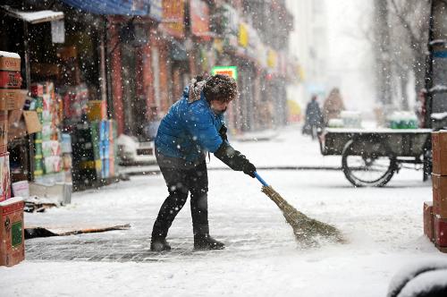 3月21日,哈爾濱市一家商鋪的店員在清掃店鋪門前的積雪。新華社記者 王凱 攝