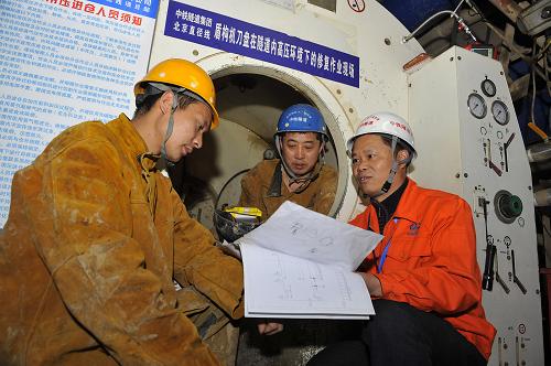 3月27日,中鐵隧道集團(tuán)的工程技術(shù)人員(右)在修復(fù)作業(yè)現(xiàn)場(chǎng)向即將進(jìn)入隧道內(nèi)高壓環(huán)境下作業(yè)的施工人員進(jìn)行技術(shù)部署。近日,由中鐵隧道集團(tuán)聯(lián)合海軍工程大學(xué)、北京工業(yè)大學(xué)、北京石油化工學(xué)院等教授和專家自主研發(fā)的盾構(gòu)機(jī)刀盤(pán)在隧道內(nèi)高壓環(huán)境下的修復(fù)技術(shù),在北京鐵路地下直徑線工程首次成功應(yīng)用,填補(bǔ)了國(guó)內(nèi)地下高壓作業(yè)空間內(nèi)盾構(gòu)機(jī)刀盤(pán)修復(fù)技術(shù)的空白。