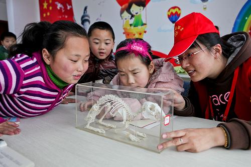 利用休息時(shí)間來做志愿者的劉華(右)在輔導(dǎo)孩子們課外活動(3月23日攝)。新華社記者 楊磊 攝