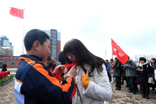 3月28日,八家子小學(xué)的學(xué)生給大學(xué)生佩戴紅領(lǐng)巾。新華社記者 楊青 攝