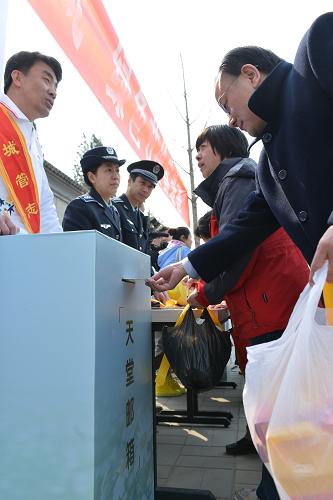 3月30日,一位市民在北京市八寶山人民公墓前,將寫有對已故親人思念與祝福的“寄往天堂的名信片”投進(jìn)“天堂郵箱”。新華社發(fā)(王全超 攝)