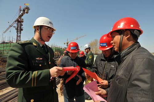 4月19日,遼寧省營口市邊防支隊警官丁闖(左一)向轄區(qū)建筑工地的外來務工人員發(fā)放宣傳單,詳細講解H7N9禽流感的防范知識。新華社發(fā)(王朝輝 攝)