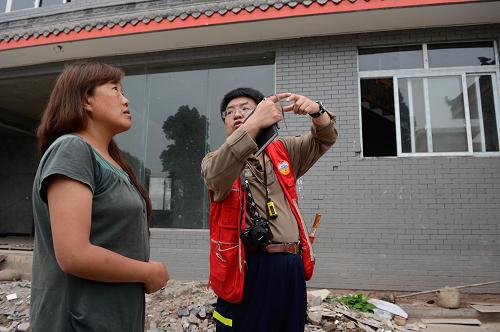 4月28日,在雅安市上里鎮(zhèn),中國地震局地質(zhì)研究所工作人員(右)在為村民說明房屋受損情況。新華社記者 李橋橋 攝