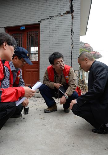 4月28日,在雅安市上里鎮(zhèn),中國地震局地質(zhì)研究所的工作人員在向村民(右)說明房屋受損情況。新華社記者 李橋橋 攝