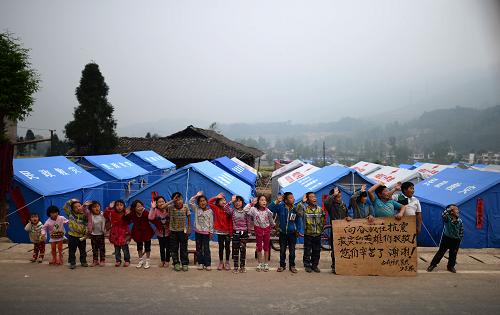 4月28日,蘆山縣龍門鄉(xiāng)古城村的孩子站在路邊向各路援助人員致謝。新華社記者 江宏景 攝