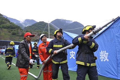5月2日,消防隊(duì)員和志愿者在模擬演練中用水槍“滅火”。新華社記者 魯鵬 攝
