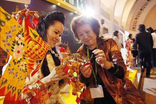 5月9日,泰國的手工藝人(左)向參觀者介紹曼谷當?shù)氐木幙椉妓?。新華社發(fā)(袁婧 攝)