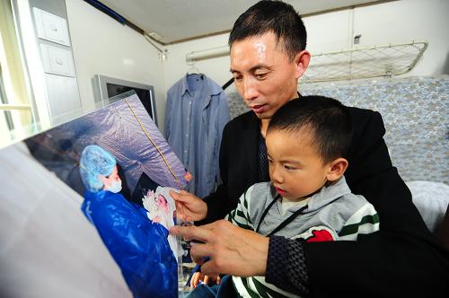 5月10日,在前往上海的列車上,父親張貴昌給小弘揚(yáng)看“兵媽媽”給他接生時(shí)的照片,講述他出生時(shí)的情形。